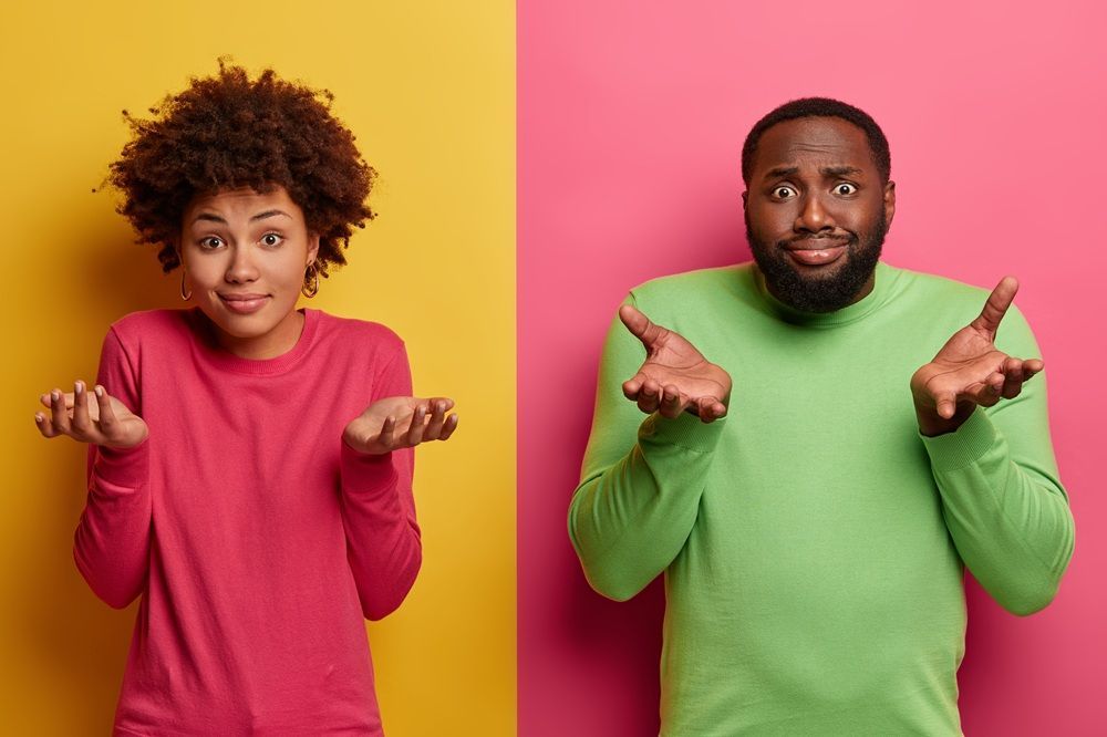 Woman in pink top and man in green top shrug, palms up. Background: yellow and pink.
