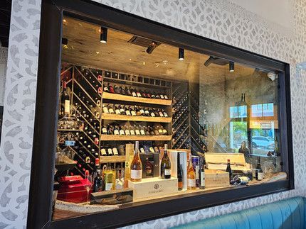 A wine cellar with lots of wine bottles behind a glass wall.