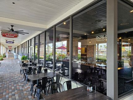 A restaurant with tables and chairs and a lot of windows.