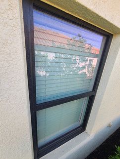 A window with blinds on it is on the side of a building.