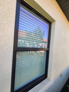 A window with blinds on it is on the side of a building.
