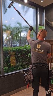 A man is cleaning a window with a long pole.