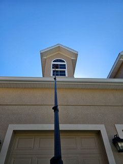 A person is cleaning the windows of a house with a watering can.