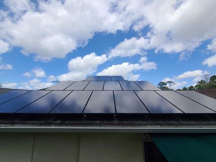 There are many solar panels on the roof of a house.