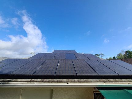 There are many solar panels on the roof of a house.