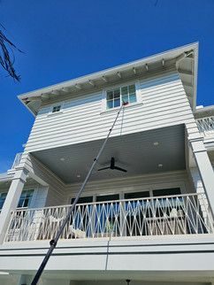A house with a balcony and a ceiling fan is being cleaned with a high pressure washer.