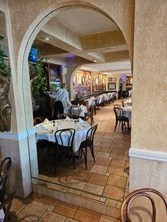 A restaurant with tables and chairs and a reflection of a person in the mirror.