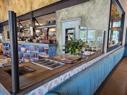 A restaurant with a long counter and a glass divider.