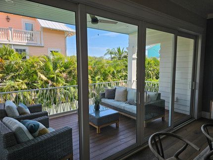 A living room with sliding glass doors leading to a balcony with a couch and chairs.