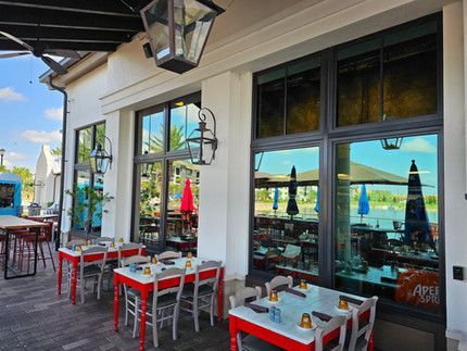 There are many tables and chairs outside of a restaurant.