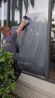 A man is cleaning a window with a sponge.