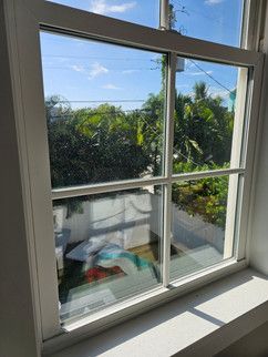 A close up of a window with a view of a house and trees.