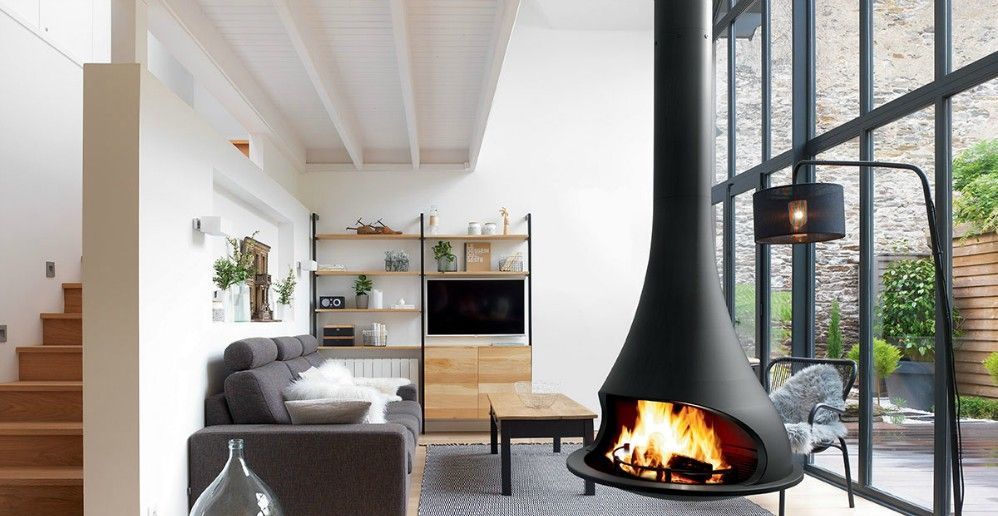 Modern living room with hanging fireplace, sofa, wooden shelves, and large windows.