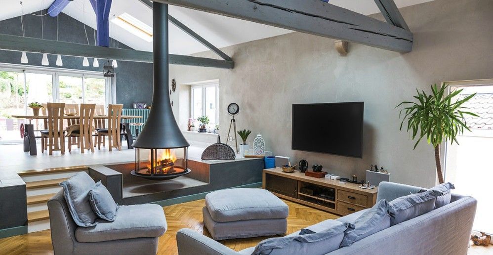 Spacious living room with a fireplace, dining area, and large screen TV. Gray furniture, wooden floor.