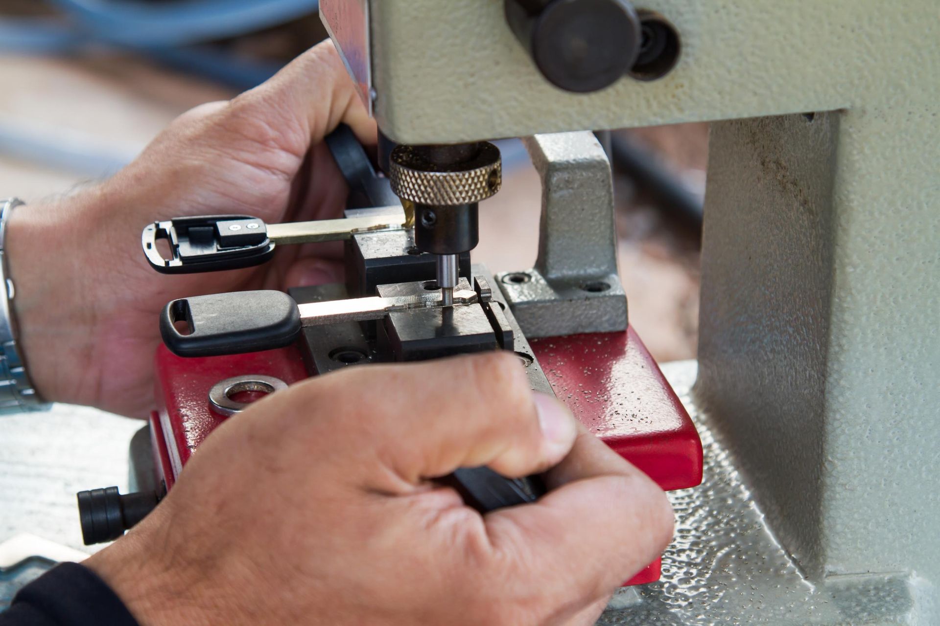 Person cutting a car key with a key-cutting machine.