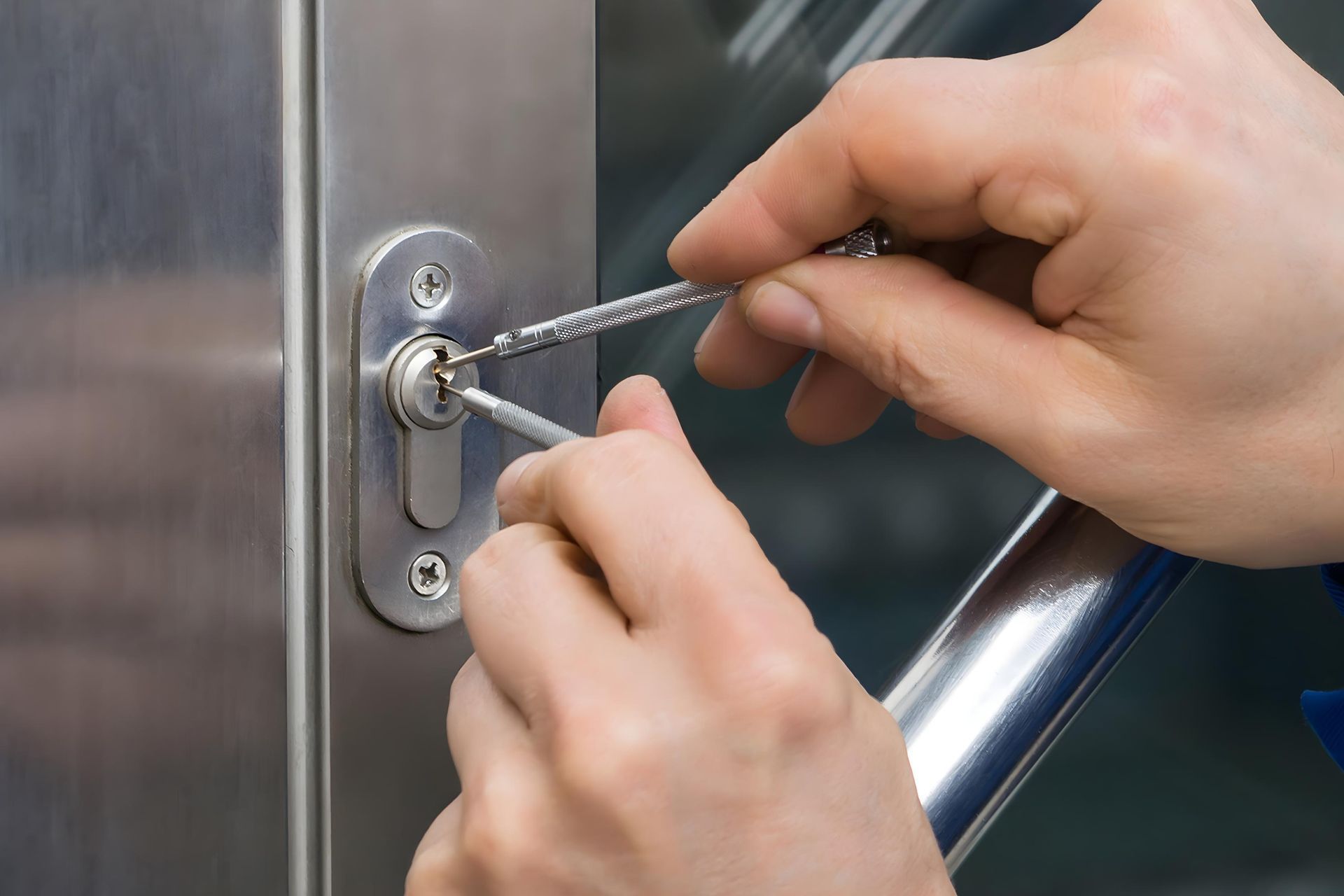 Hands using lock picks on a door lock.