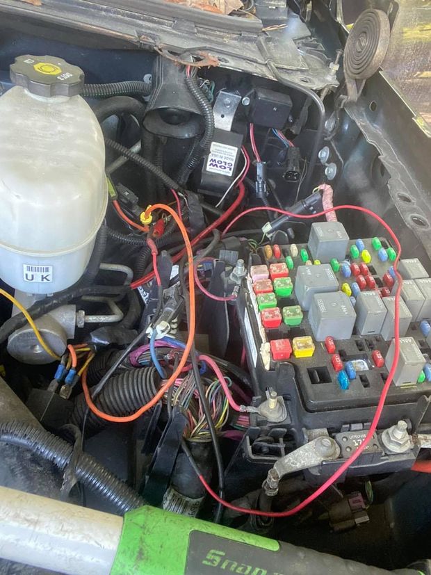 Engine bay with wiring, fuse box, and brake fluid reservoir.
