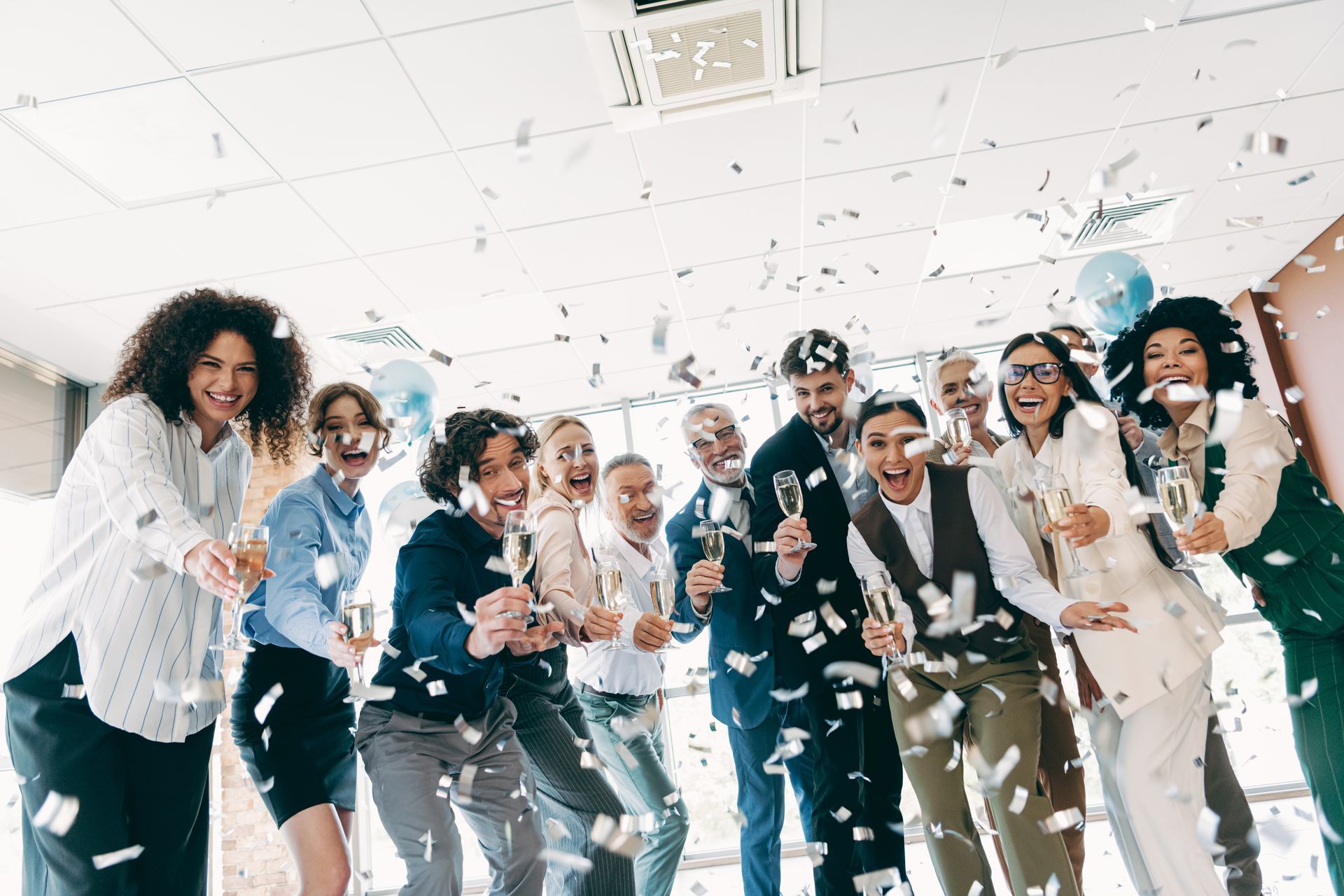 Office workers celebrate with champagne and confetti.