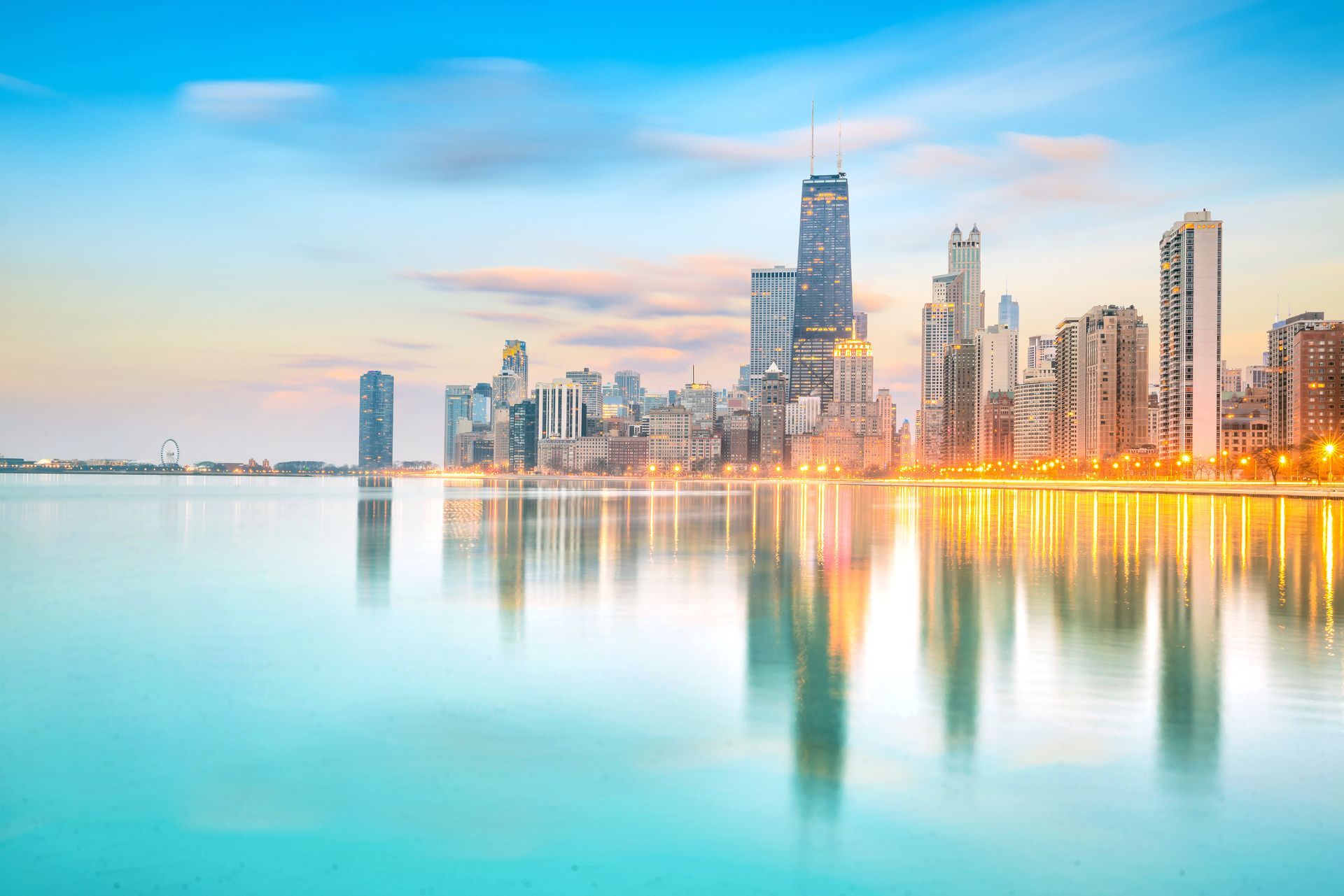 Sunrise skyline with tall buildings reflecting on calm turquoise water