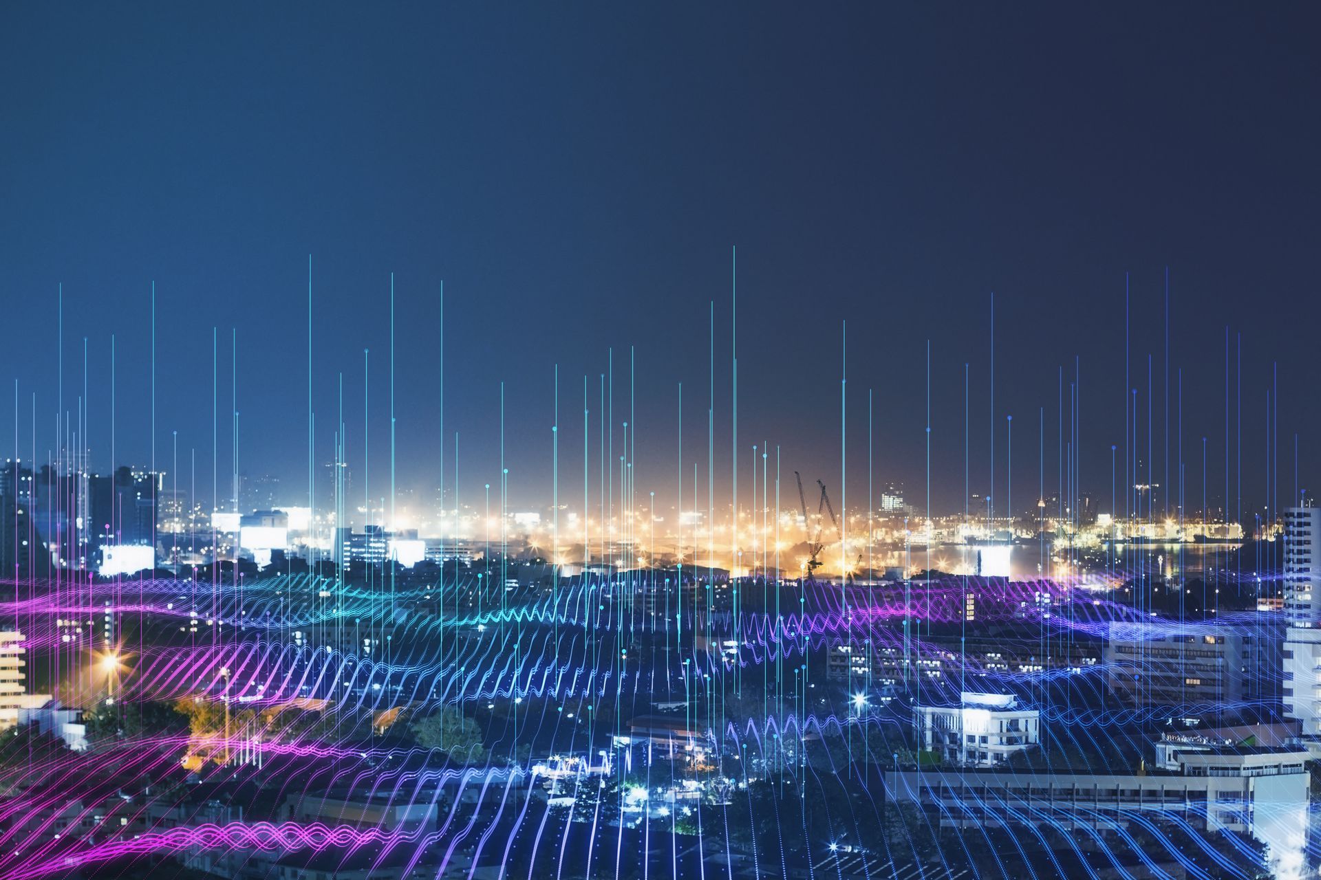 A night cityscape overlaid with a glowing, colorful digital grid and vertical light beams representing data connectivity.