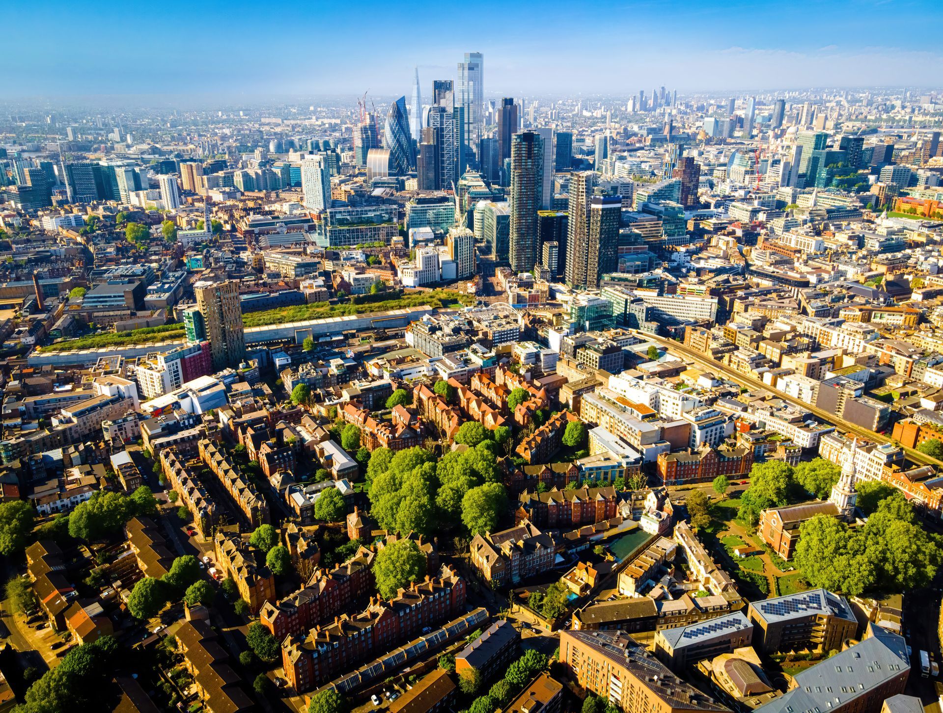 Aerial view of the London skyline with modern skyscrapers looming over dense, historic residential streets.