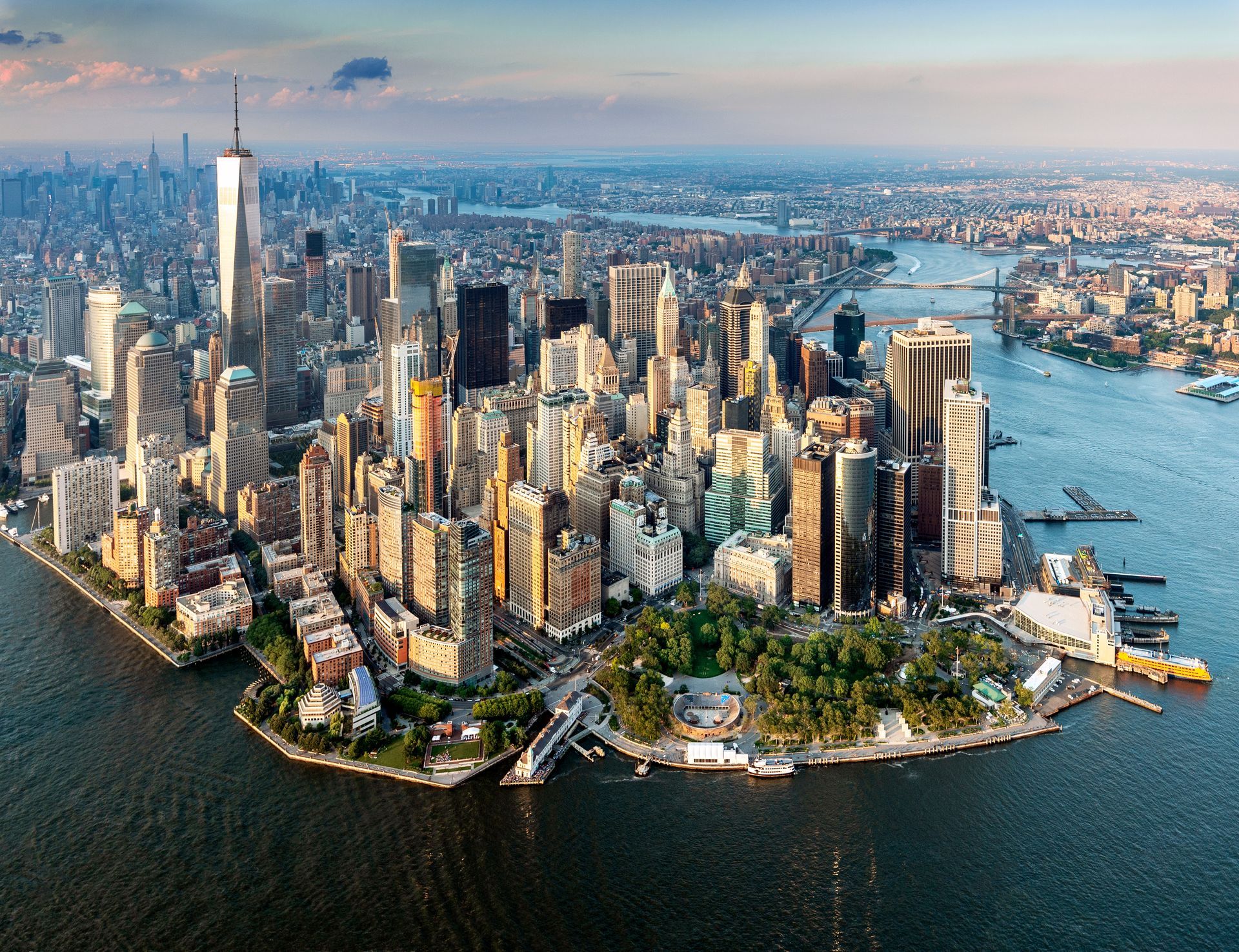 Aerial view of Lower Manhattan skyline with skyscrapers and surrounding water at sunset