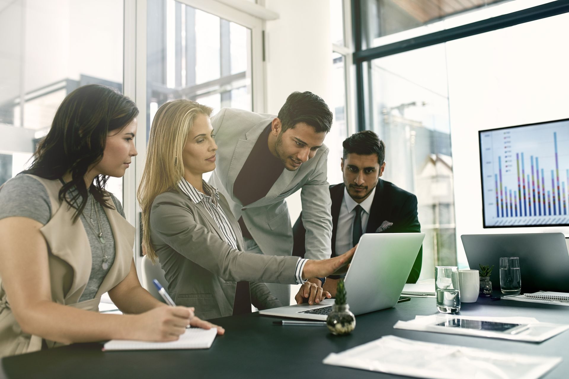 Business team reviewing data on laptop in bright office.