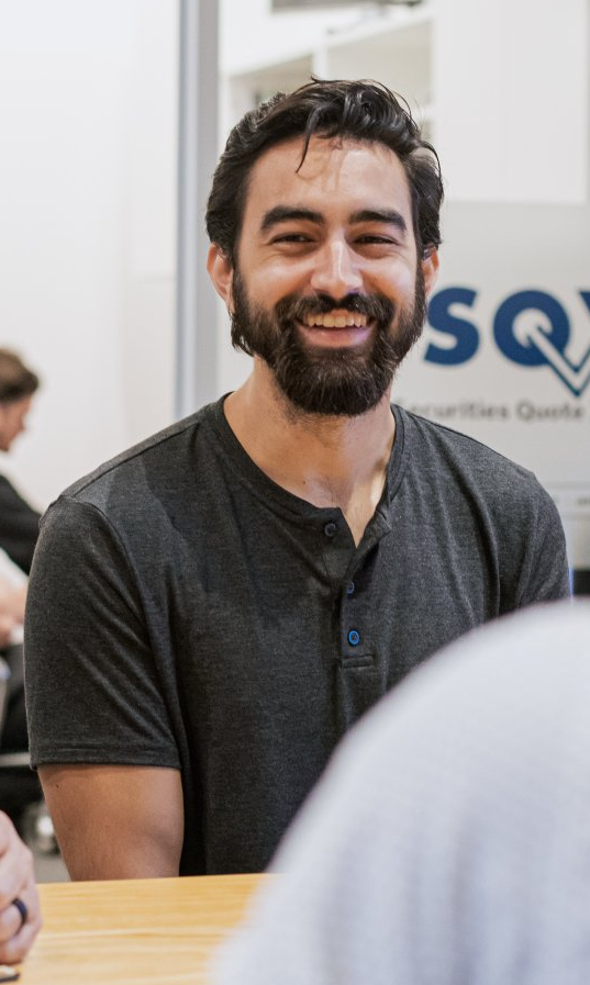 A man with a beard is smiling while sitting at a table.