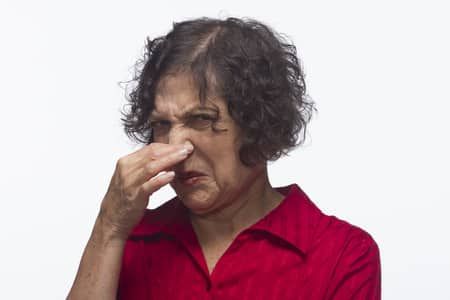 Woman in a red shirt pinching her nose