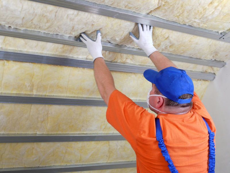 Man in safety gear installing insulation