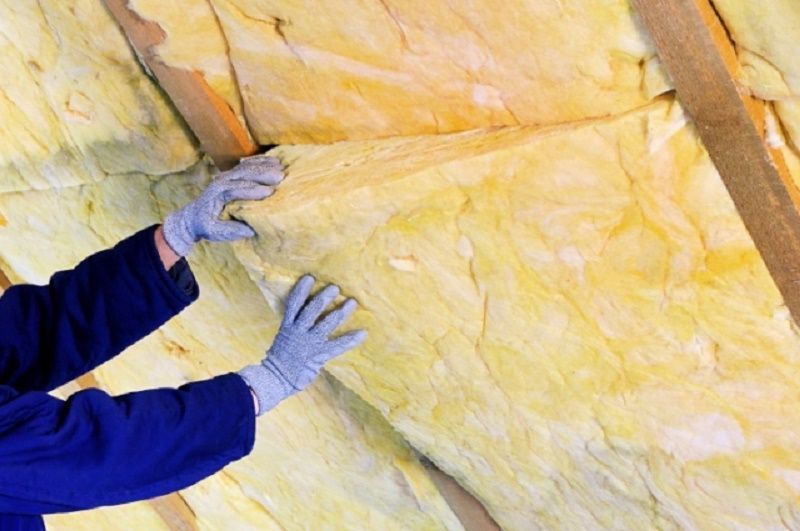 Person wearing gloves installing yellow insulation