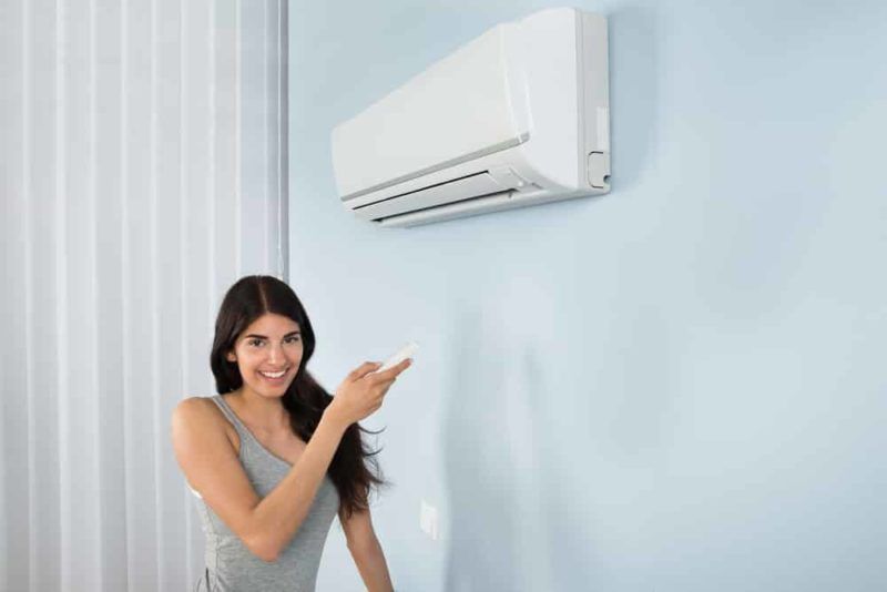 Happy woman with remote of air conditioner