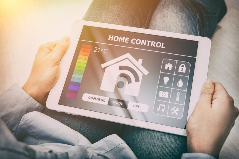 Person holding tablet displaying a Home control interface