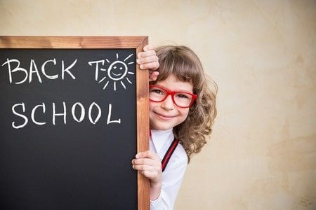 Girl with red glasses peeking from behind a chalkboard