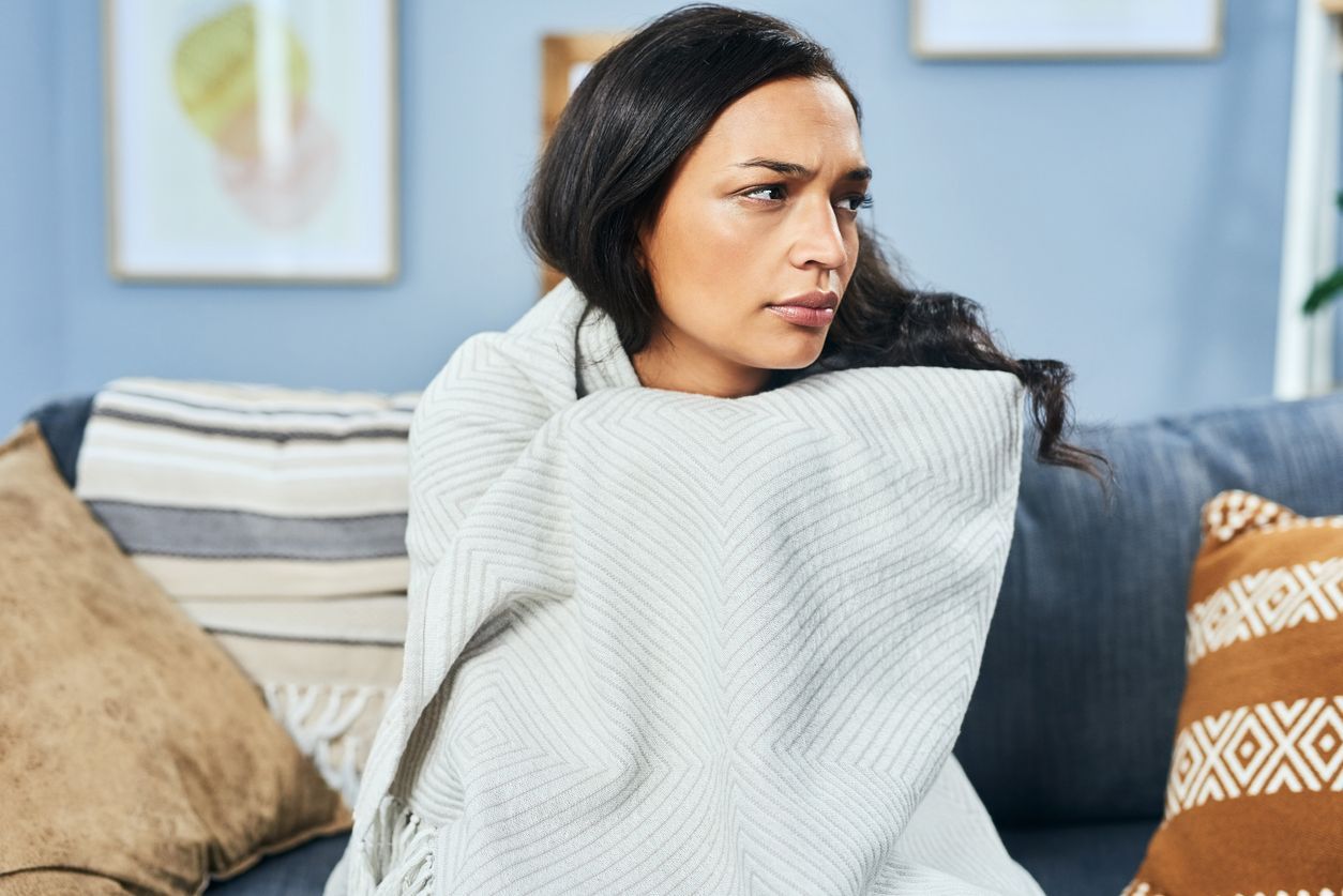 Woman wrapped in a blanket, sitting on a sofa