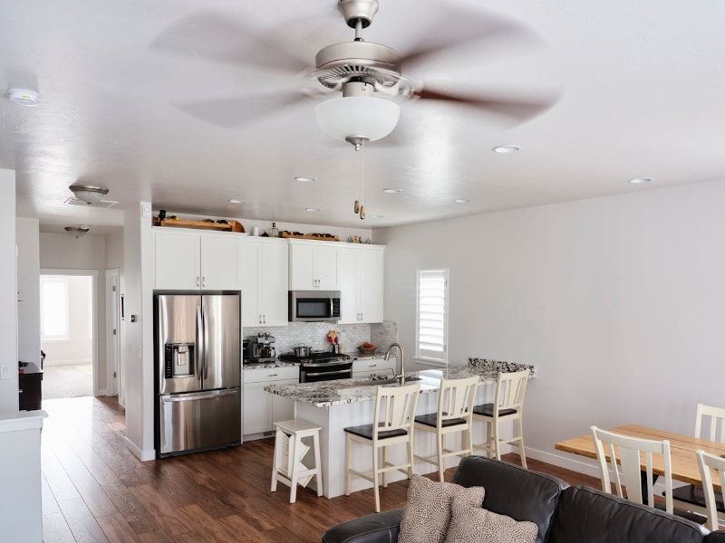 Bright kitchen with island, stainless steel appliances, and ceiling fan