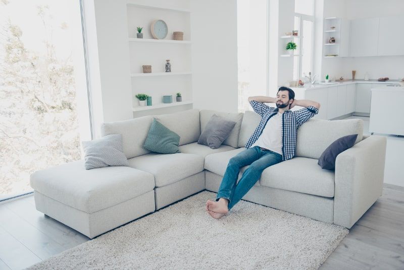 Man relaxes on a white sectional sofa