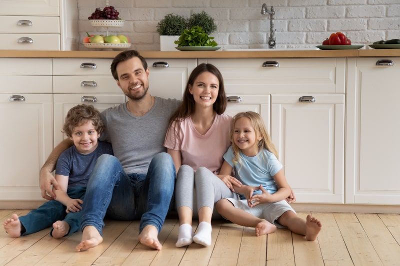 Happy family of four sitting on a kitchen floor