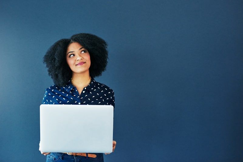 Woman with curly hair holds laptop