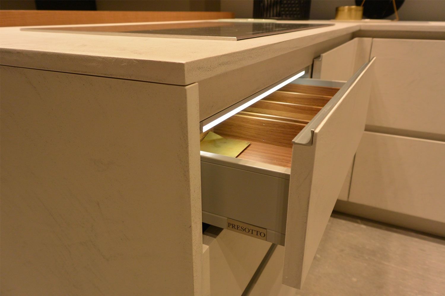 Cassetto aperto in un mobile da cucina beige, che mostra l'organizer interno in legno.