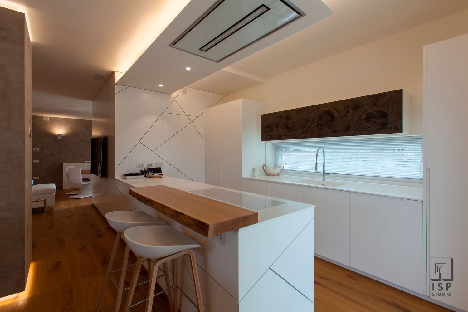 Cucina moderna con mobili bianchi, isola centrale in legno, sgabelli da bar e faretti a incasso a soffitto.