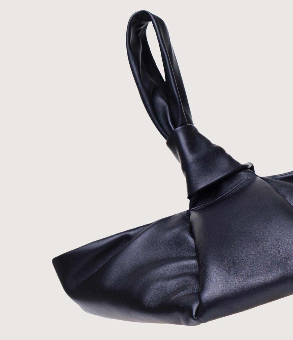 A black leather bag with a knotted handle on a white background.