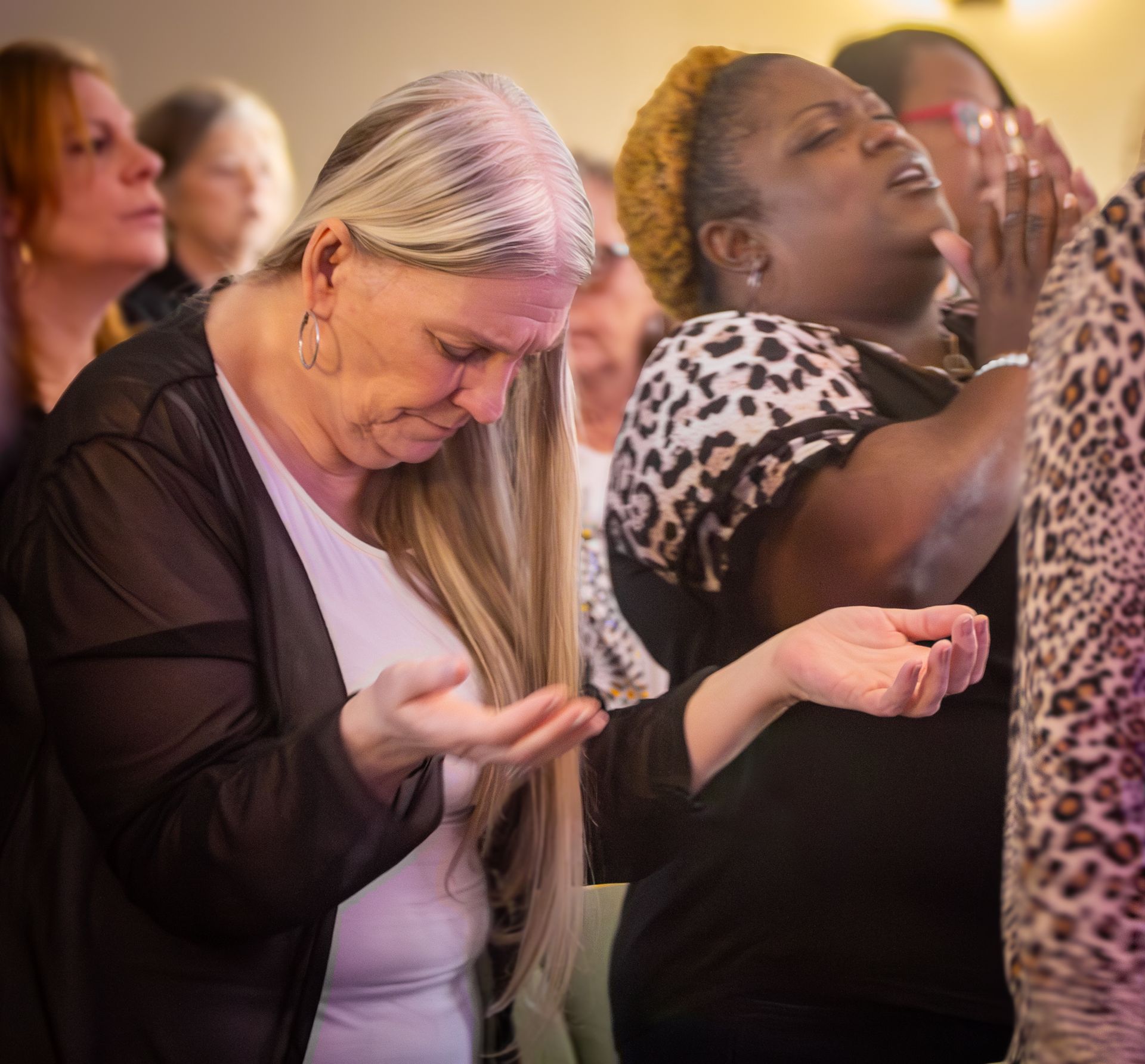 A woman in a blue and white dress holds her hands out in prayer