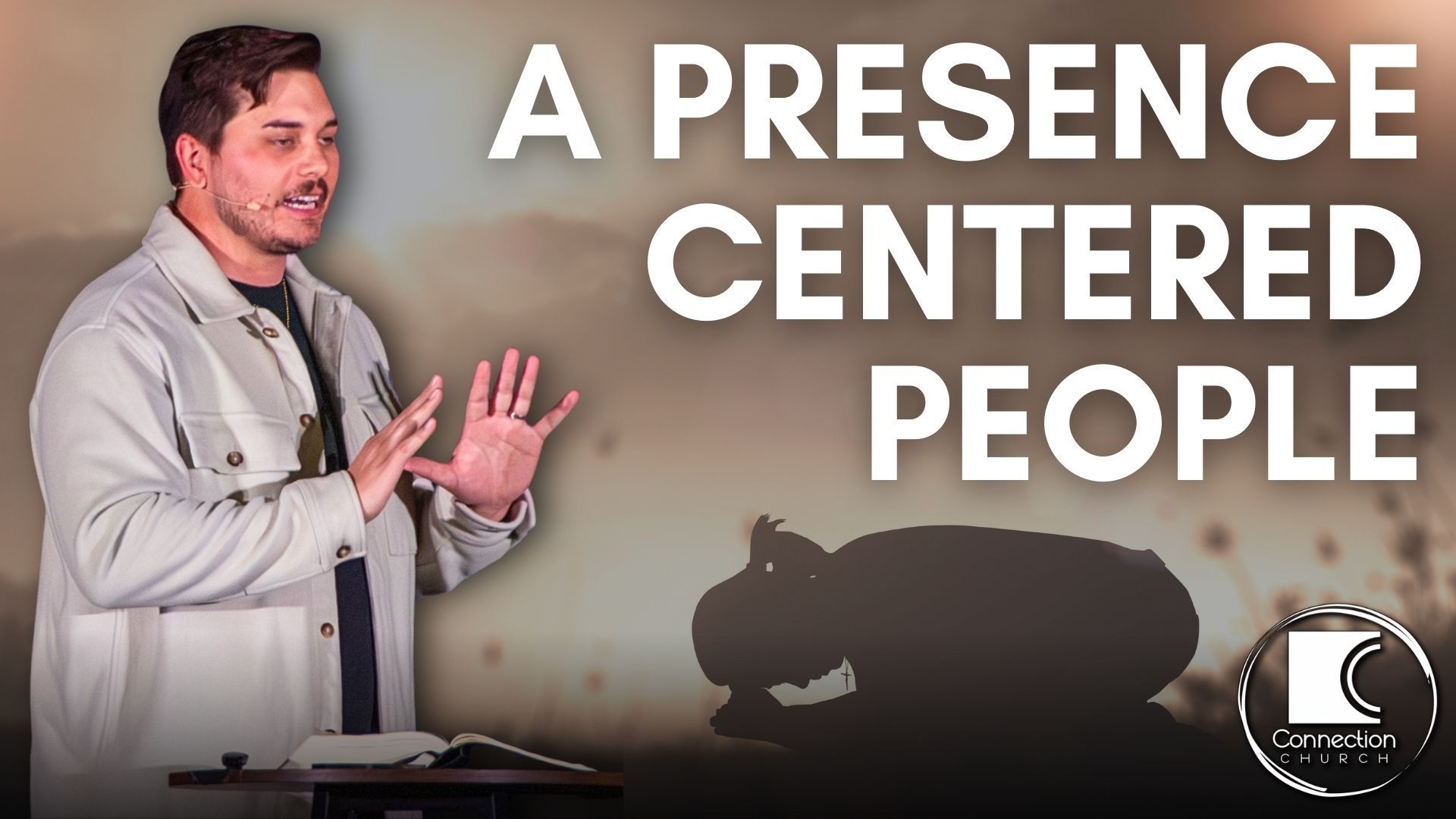 Man speaking, hands raised, before open book. Text: 