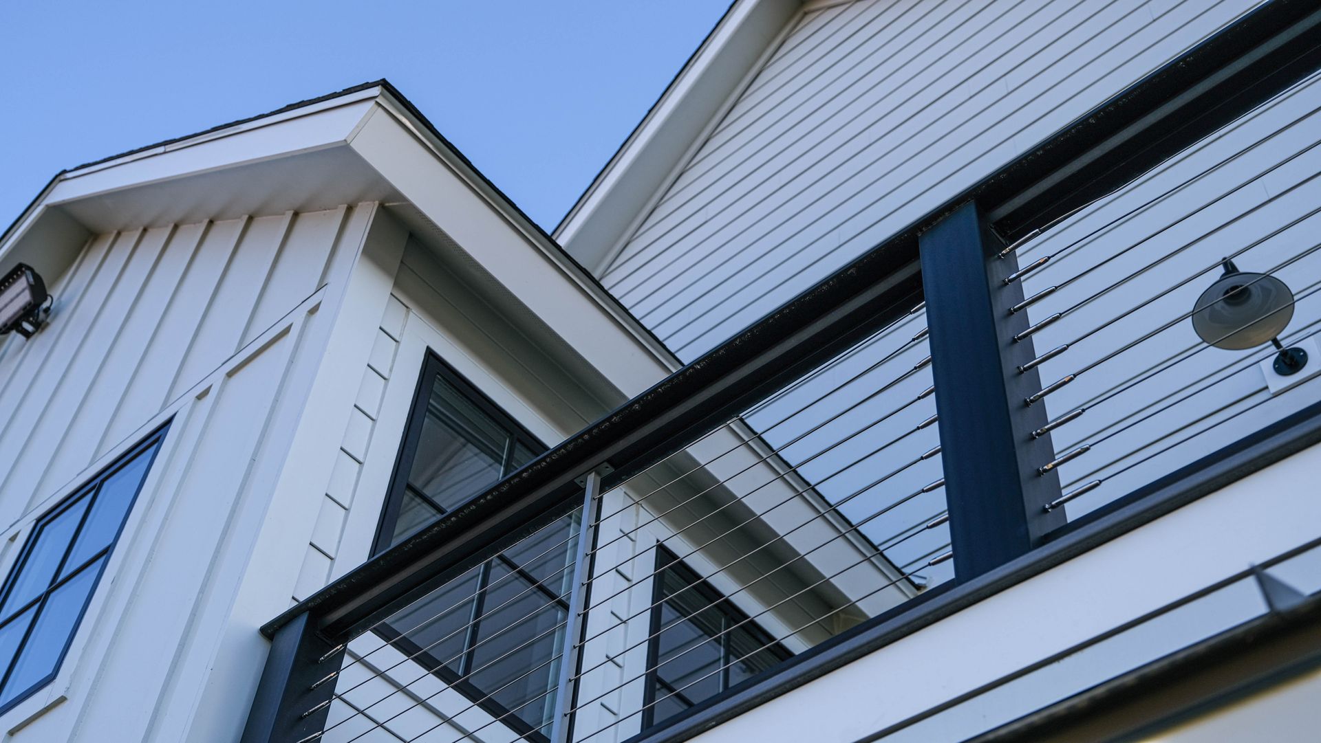 White house exterior with black railing, blue sky.