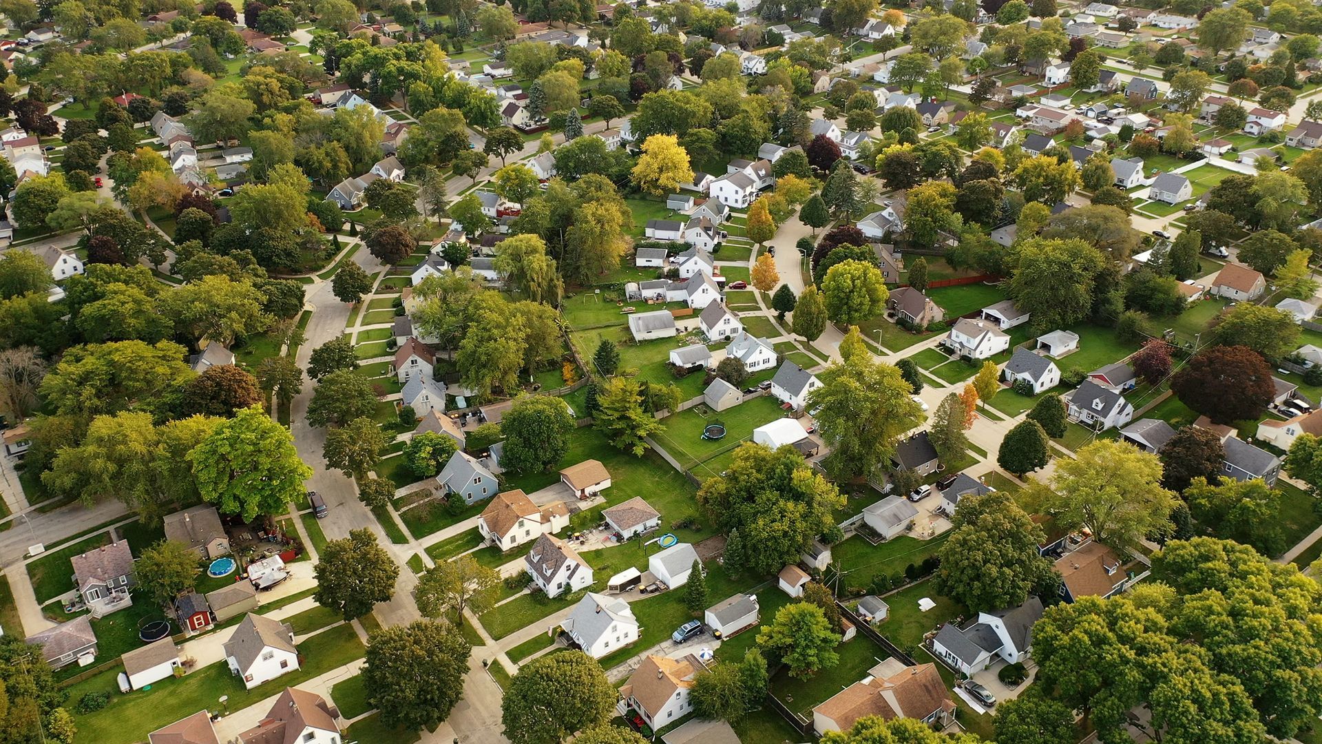 Aerial view of a residential neighborhood with houses and lush green trees. Aerial view of a residential neighborhood with houses and lush green trees.