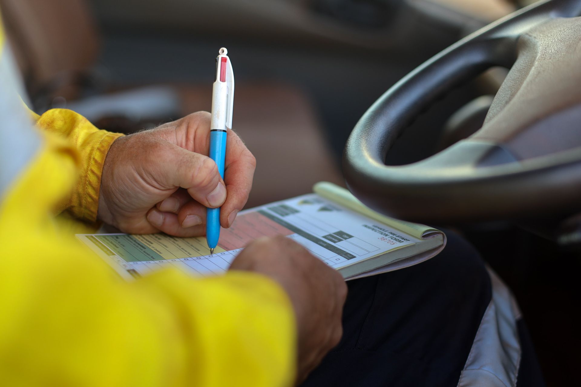 A Person Is Sitting in A Car Writing on A Piece of Paper with A Pen — Steve Purse Automotive In St. Georges Basin, NSW
