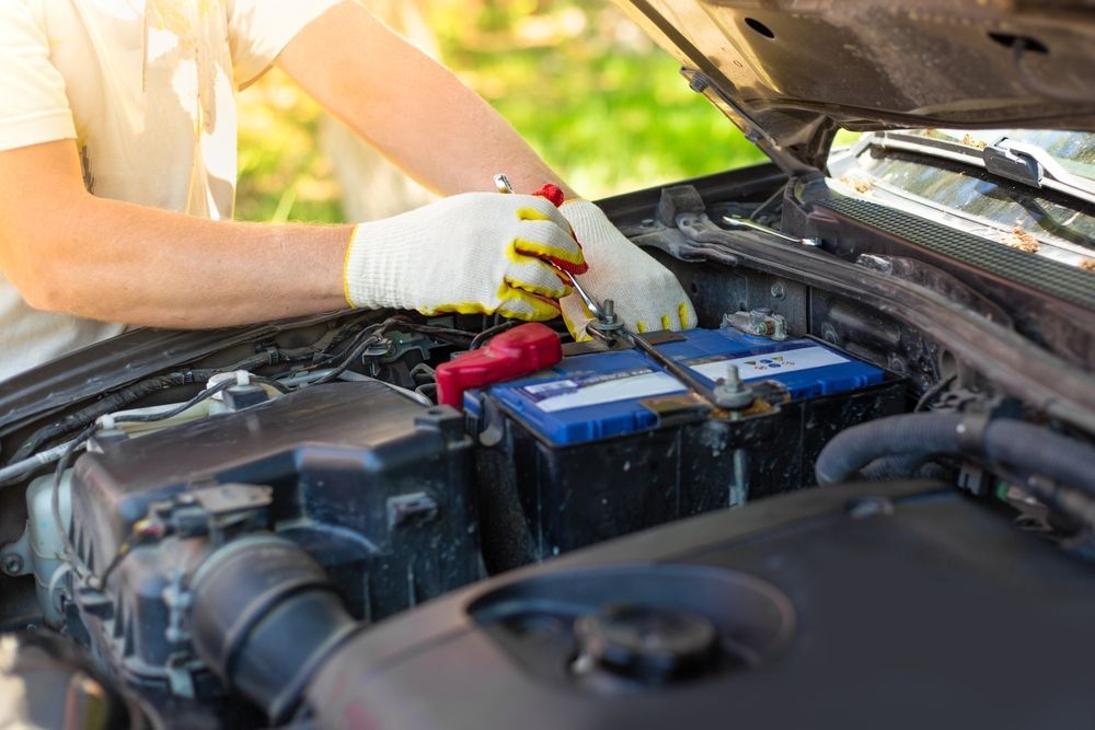 A Man Is Repairing a Car Battery with A Wrench — Steve Purse Automotive In St. Georges Basin, NSW
