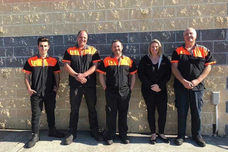A Group of People Standing in Front of A Brick Wall — Steve Purse Automotive In Huskisson, NSW
