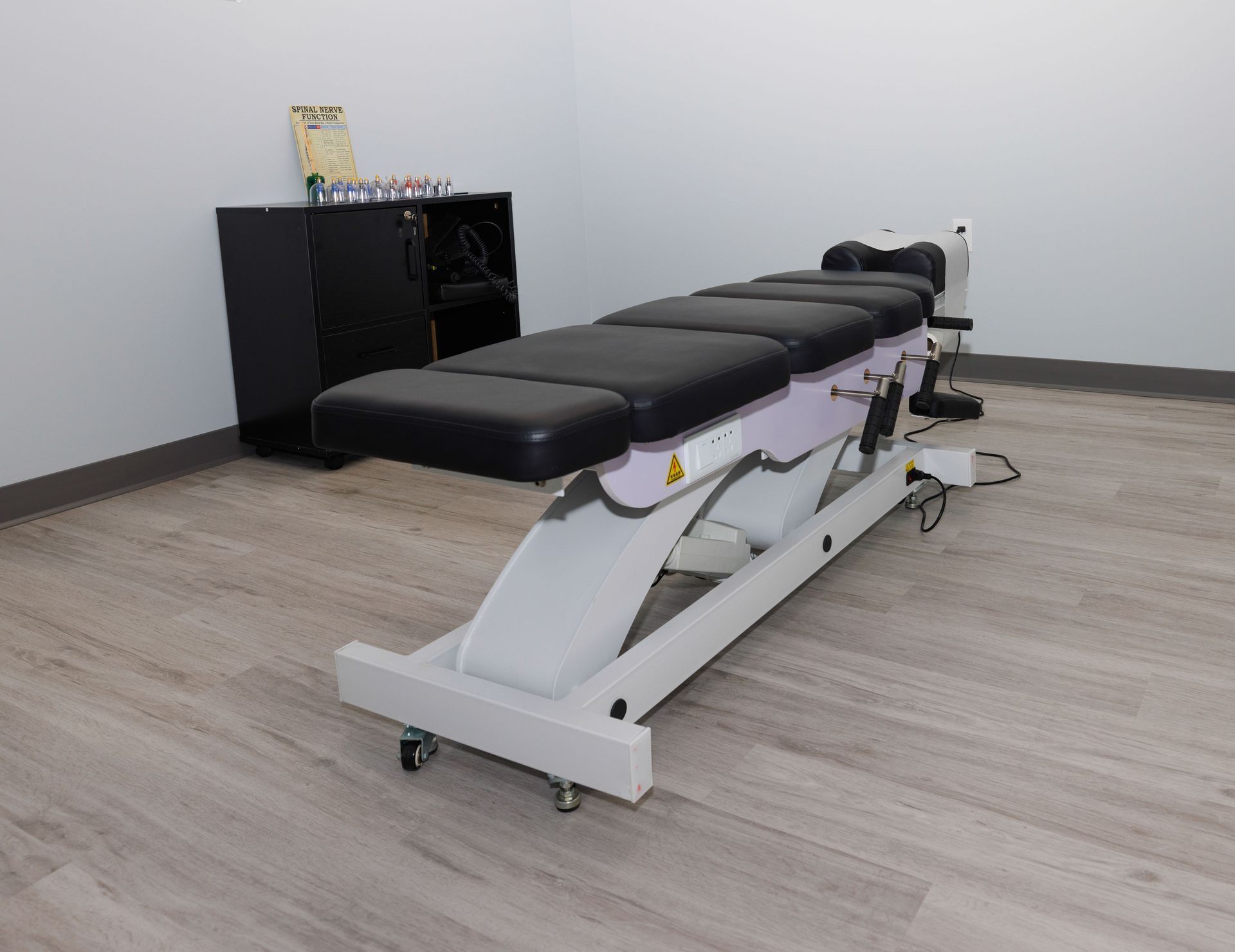 a chiropractic table is sitting in a room with a wooden floor .